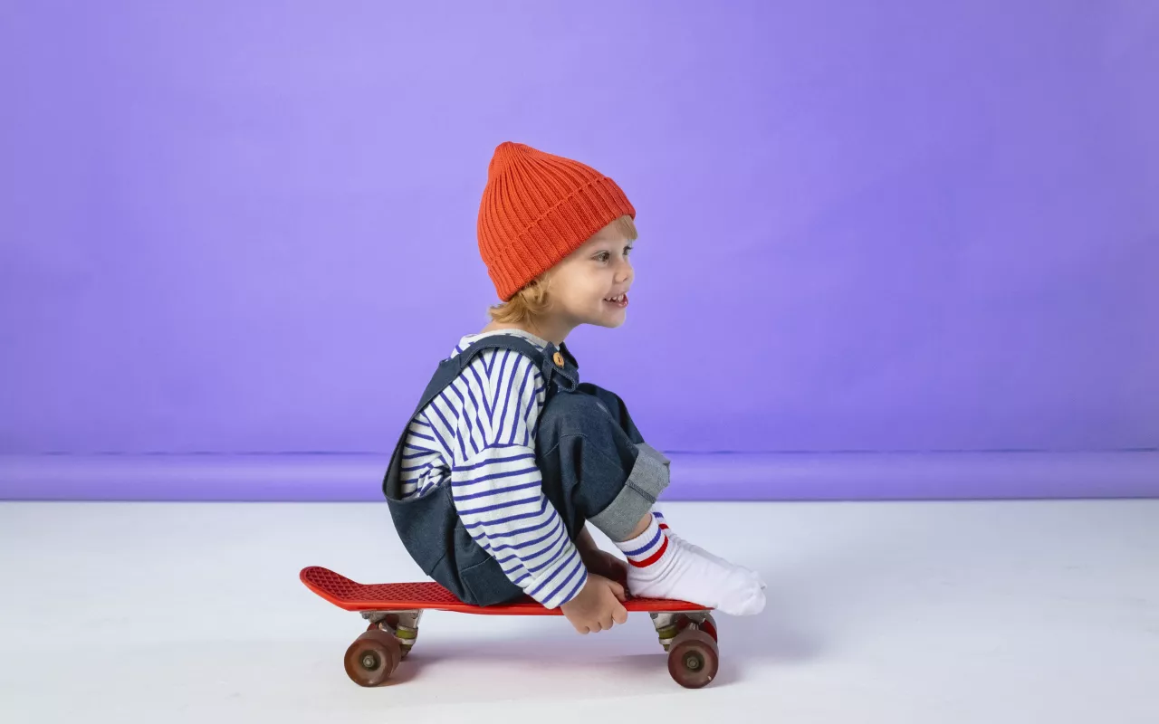 Ein Kleinkind sitzt auf einem Skateboard und rollt los. 