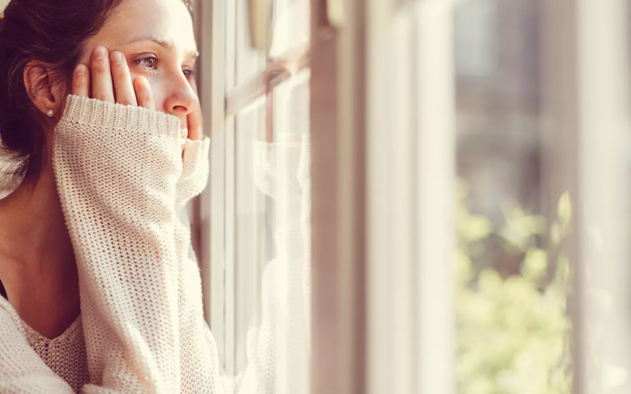 Eiene Frau die traurig aus dem Fenster schaut