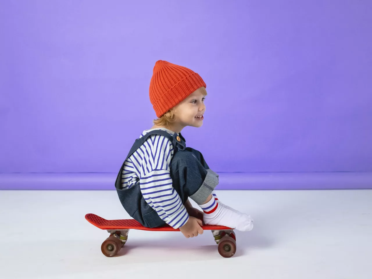 Ein Kleinkind sitzt auf einem Skateboard und rollt los. 