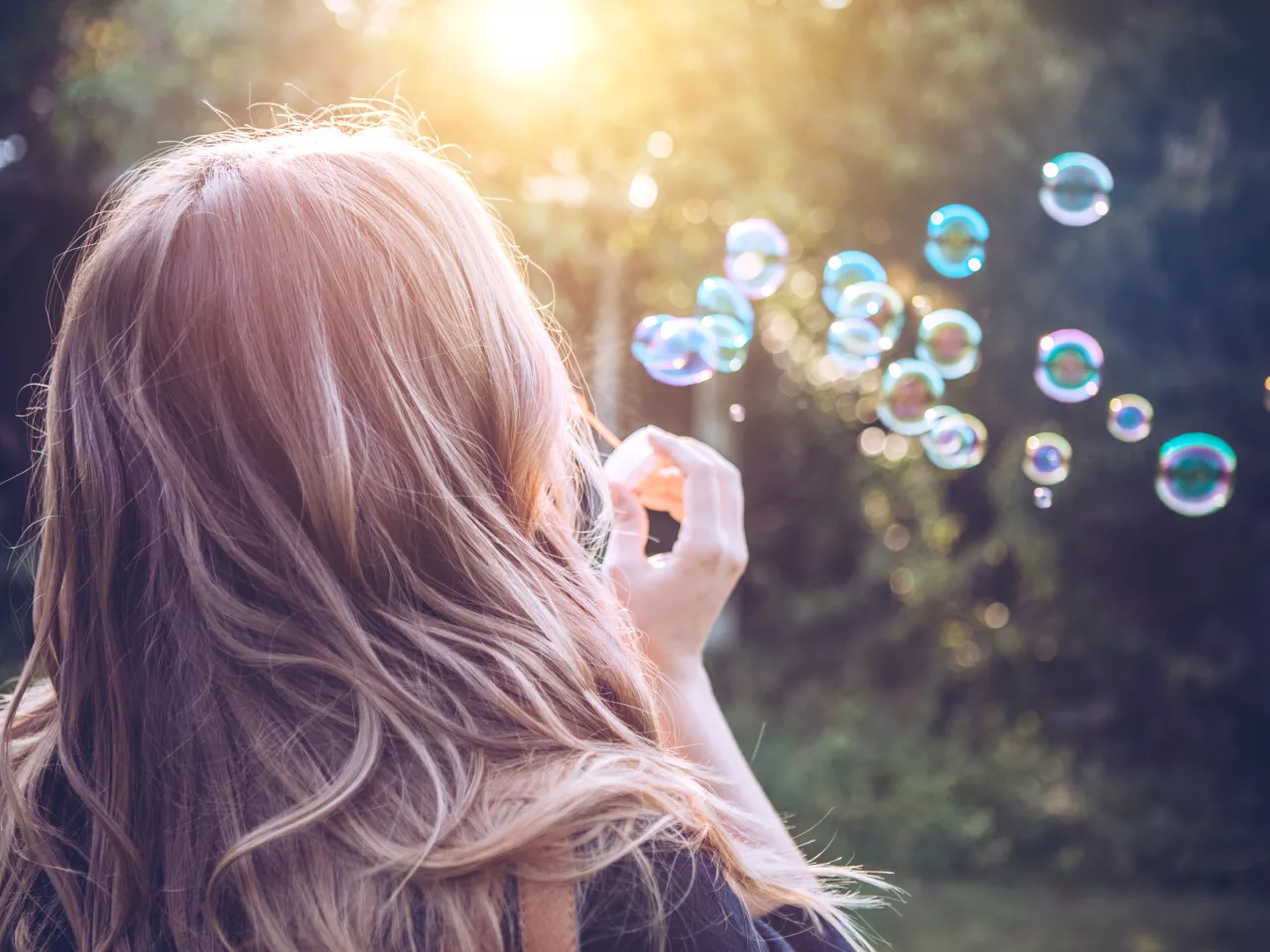 Eine Frau mit Kinderwunsch pustet Seifenblasen. 