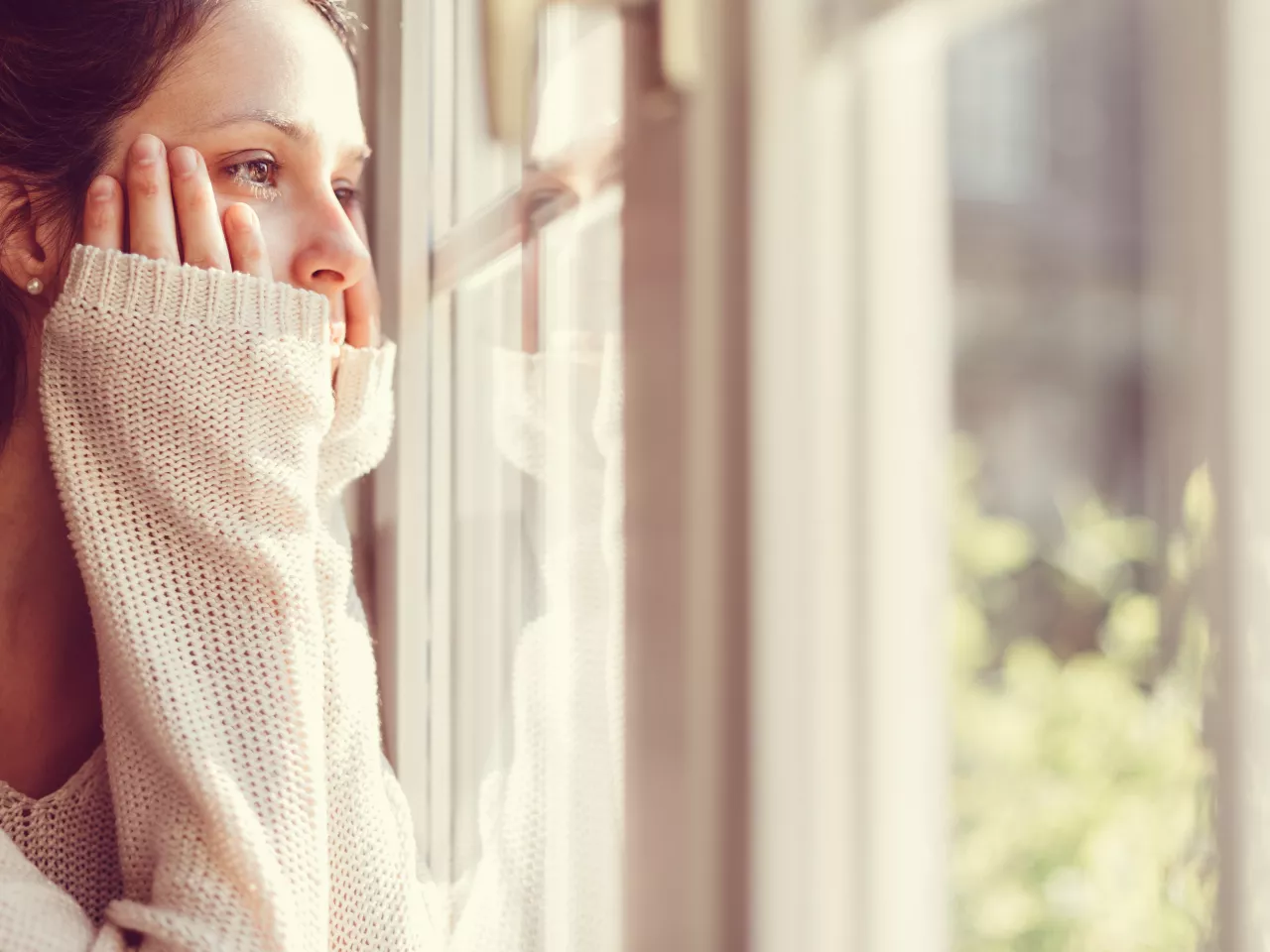 Eiene Frau die traurig aus dem Fenster schaut