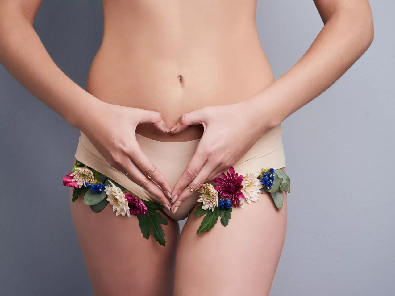 Frau Formt ihre Hände vor Ihrem Unterleib zu einem Herzen